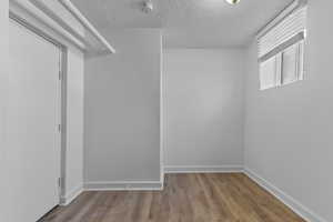 Unfurnished room featuring a textured ceiling, wood finished floors, and a smoke detector
