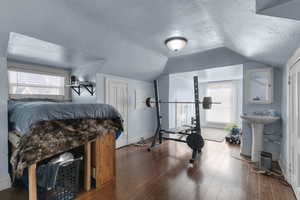 Workout room with a textured ceiling, plenty of natural light, wood finished floors, and vaulted ceiling