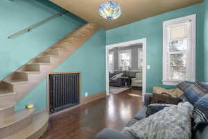 Living area with stairway, radiator heating unit, and hardwood / wood-style floors