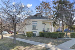 View of front of property featuring brick siding, covered porch, and a shingled roof