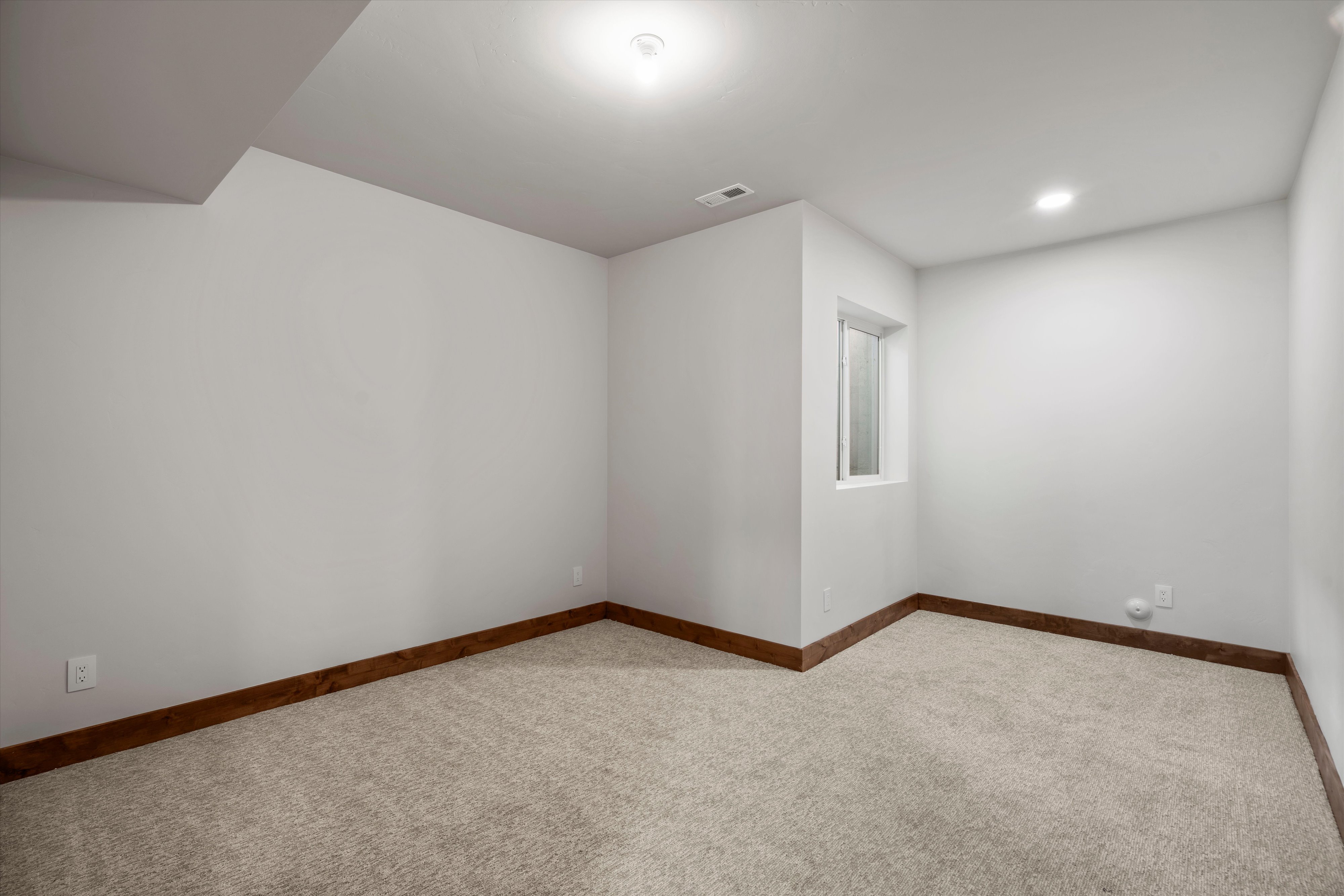 Carpeted room featuring white walls, recessed lighting, and a white-framed window