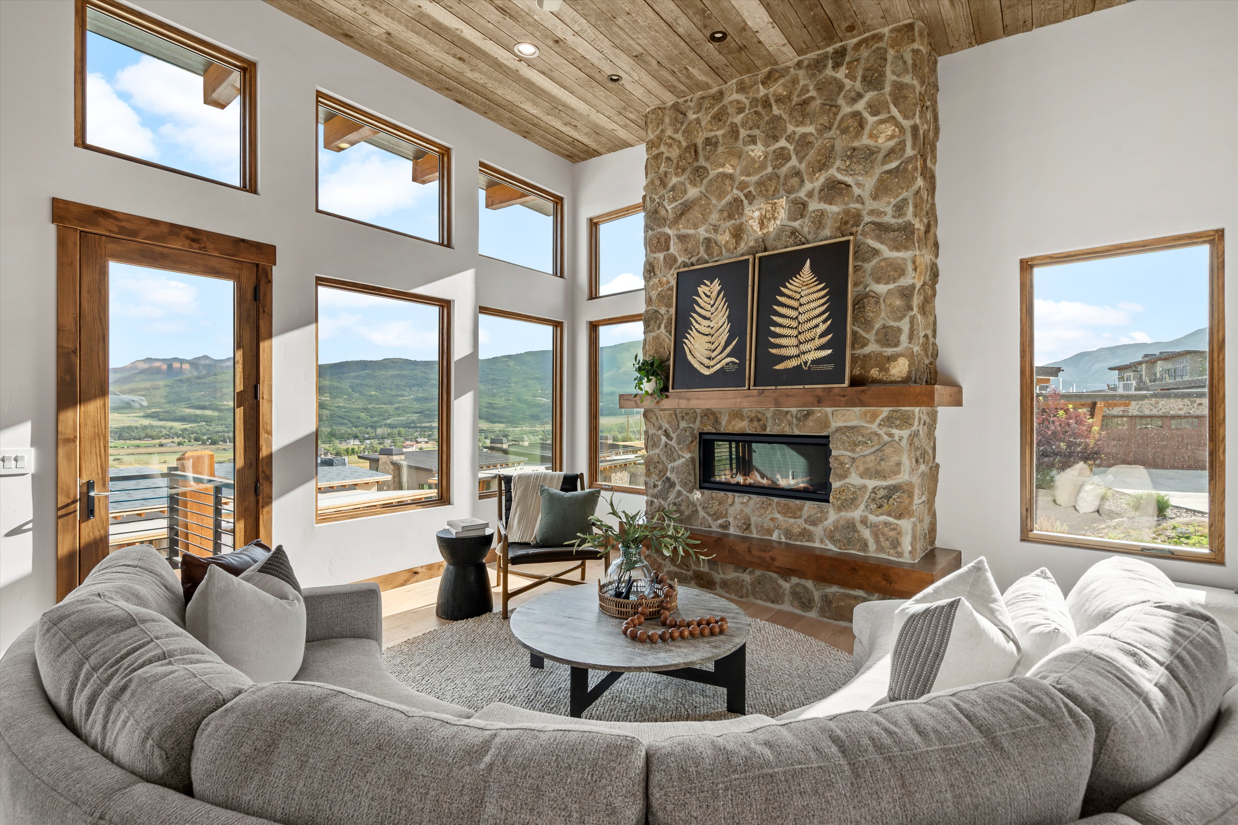 Living area with a floor-to-ceiling stone fireplace, wood mantle, and an integrated horizontal electric fireplace