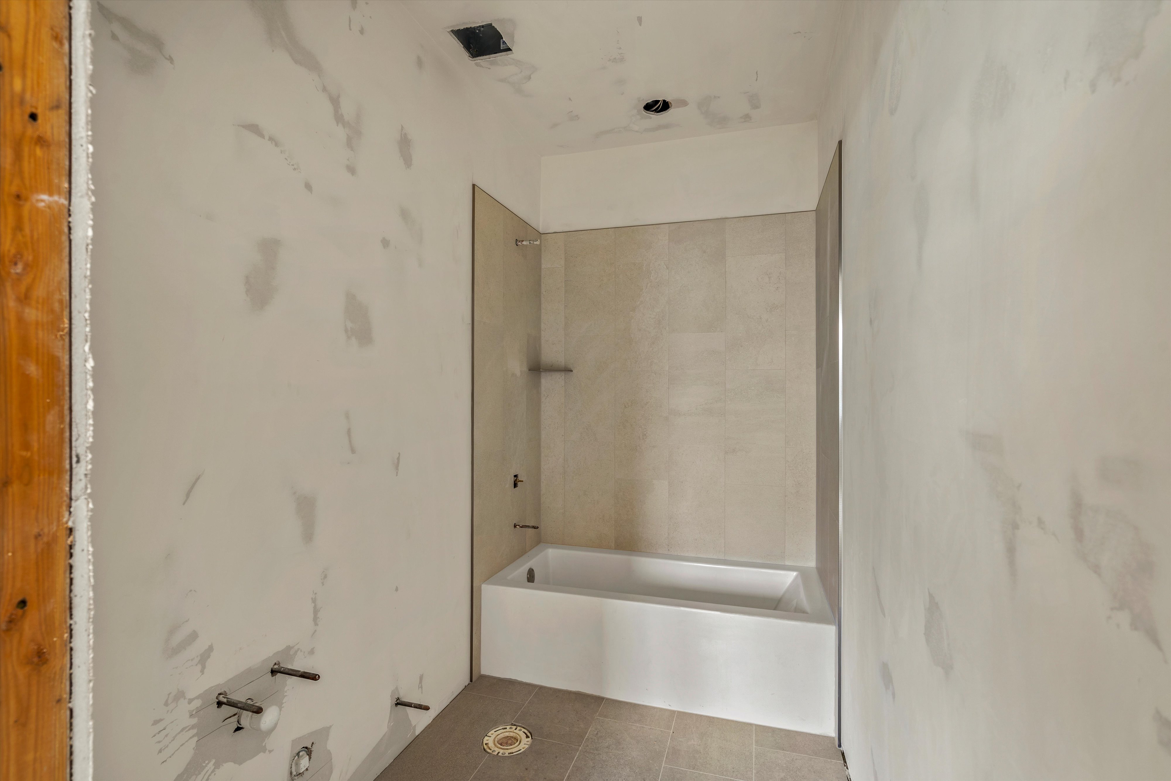 Newly installed bathtub with tile surround and glass partition