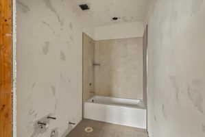Newly installed bathtub with tile surround and glass partition