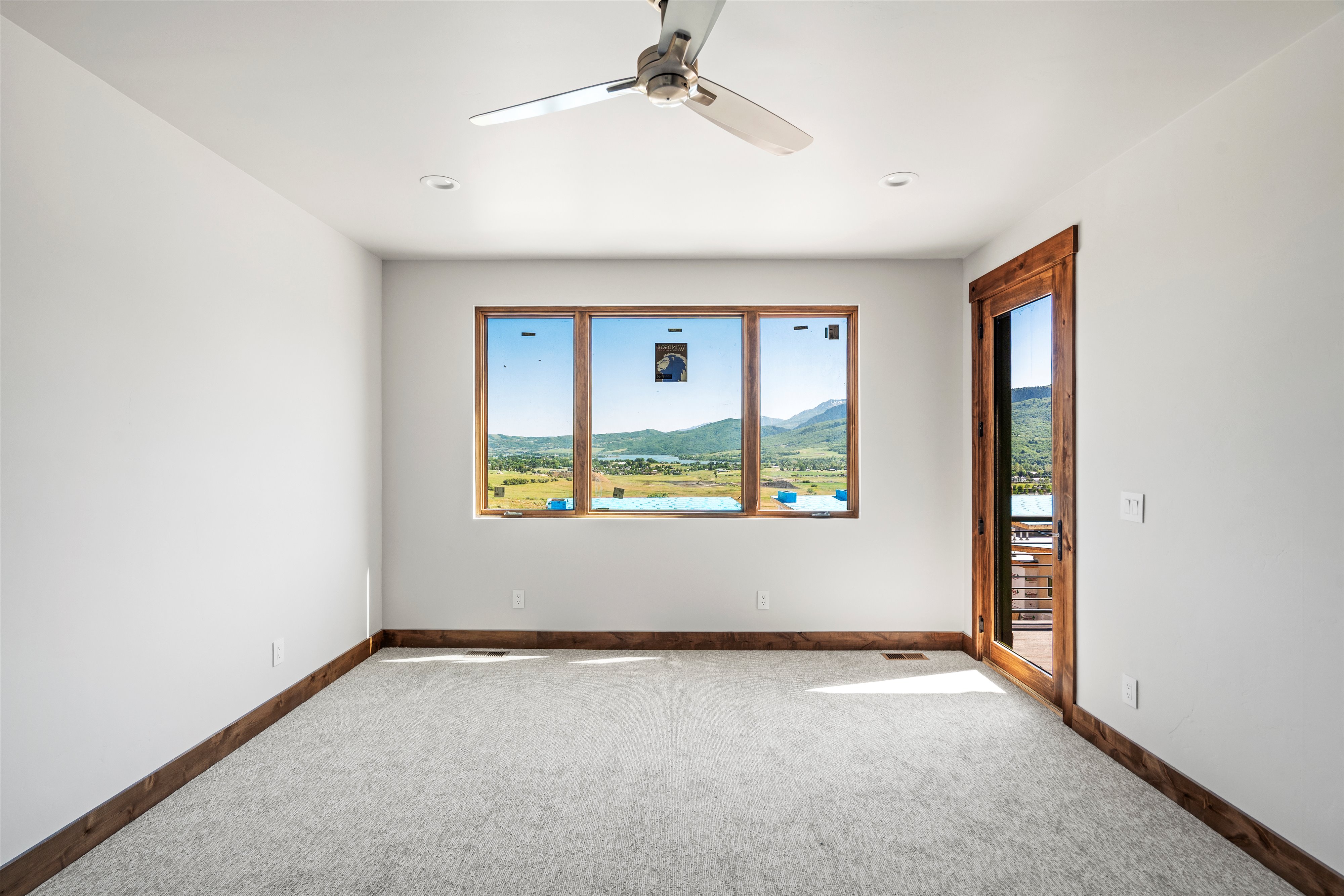 Spacious room featuring broad picture windows, a wood-framed glass door, and recessed lighting