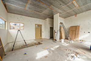 Entryway featuring a partially finished ceiling, two distinct window openings, a light-colored entry door with glass panels, and an open floor plan