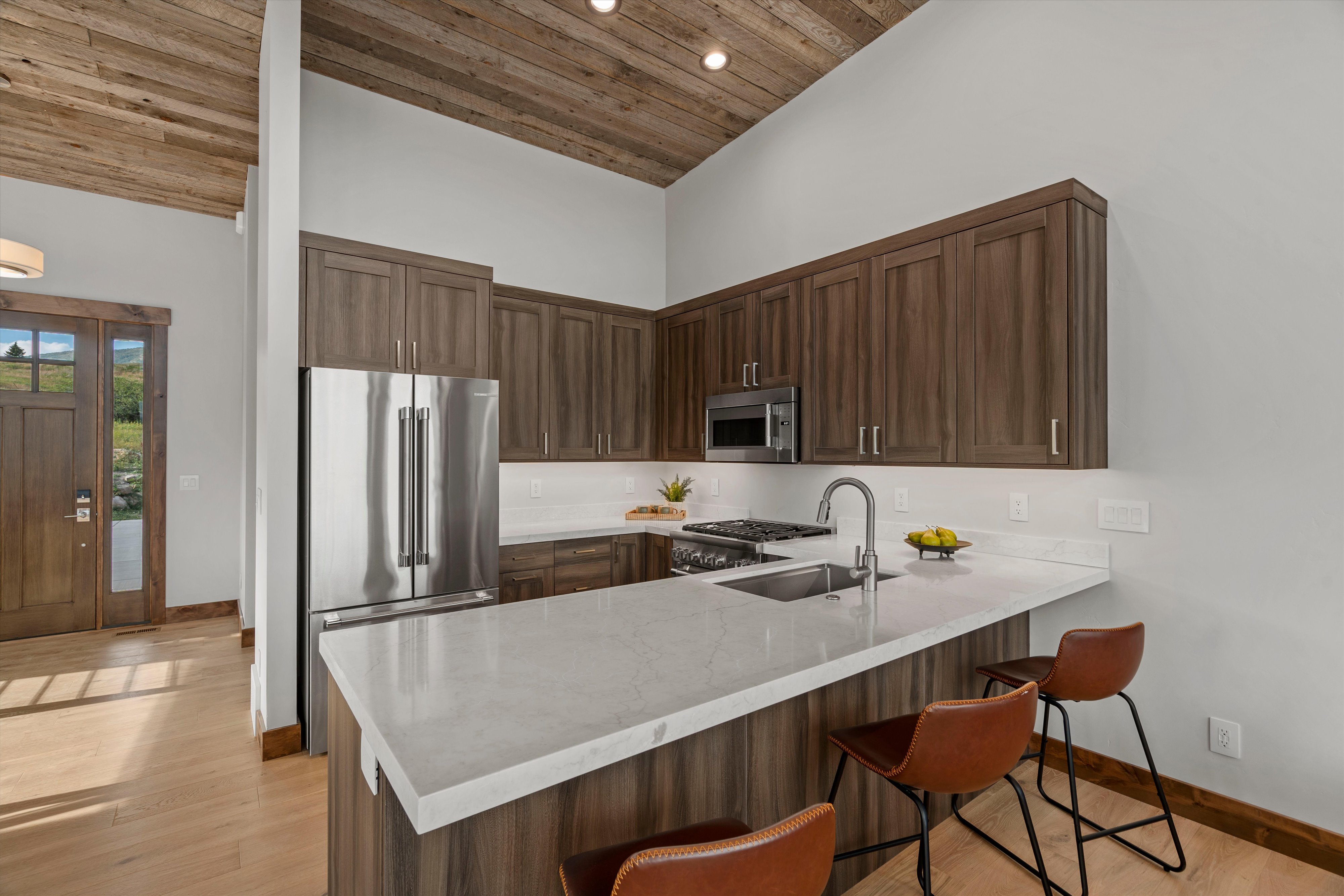 Modern kitchen featuring wood-finish cabinetry, stainless steel appliances, and light-toned countertops