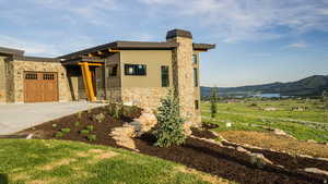 View of front of property with stone siding, concrete driveway, a mountain view, a garage, and a front yard