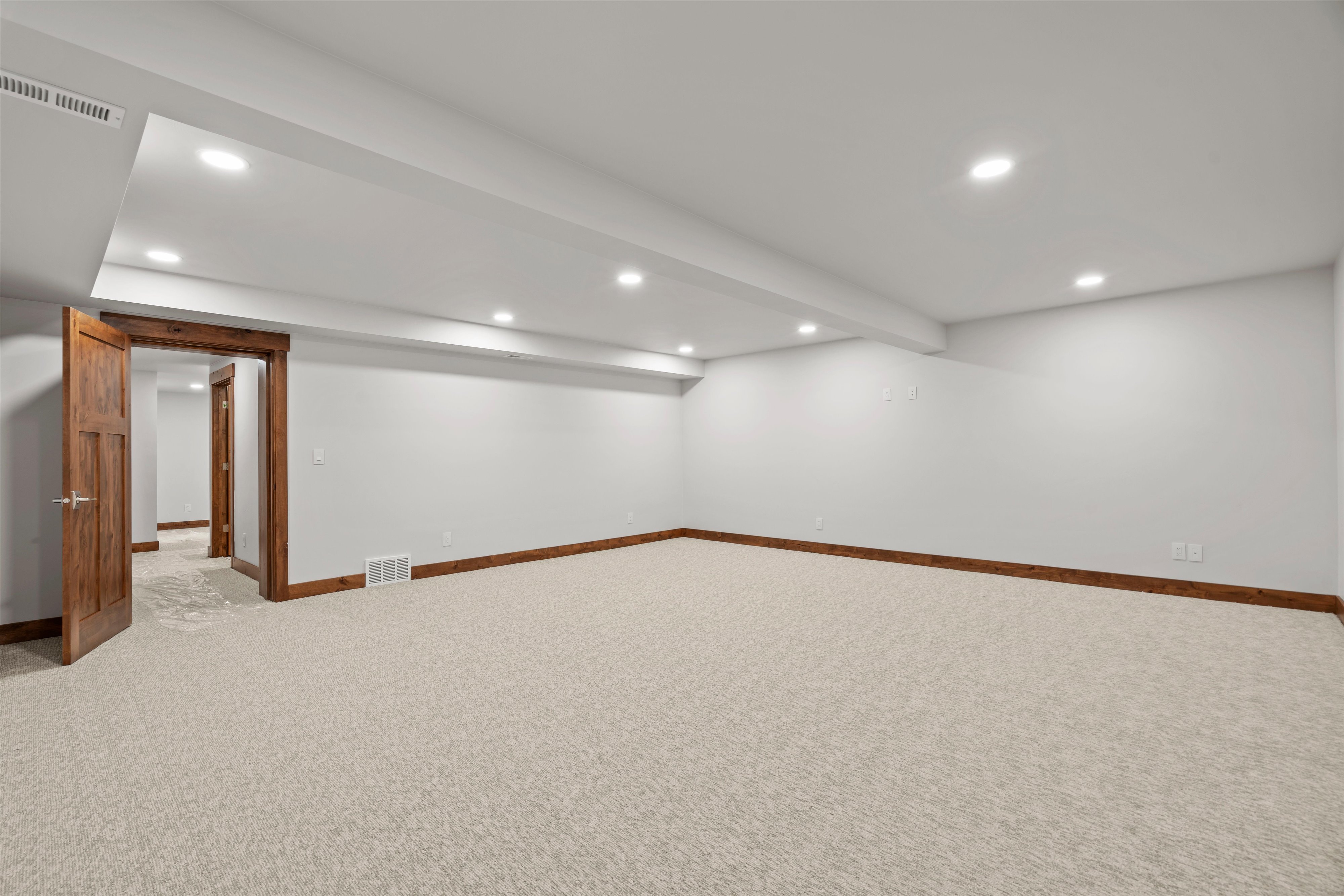Spacious room featuring neutral carpeting, white walls, recessed ceiling lighting, and solid wood interior doors with matching trim