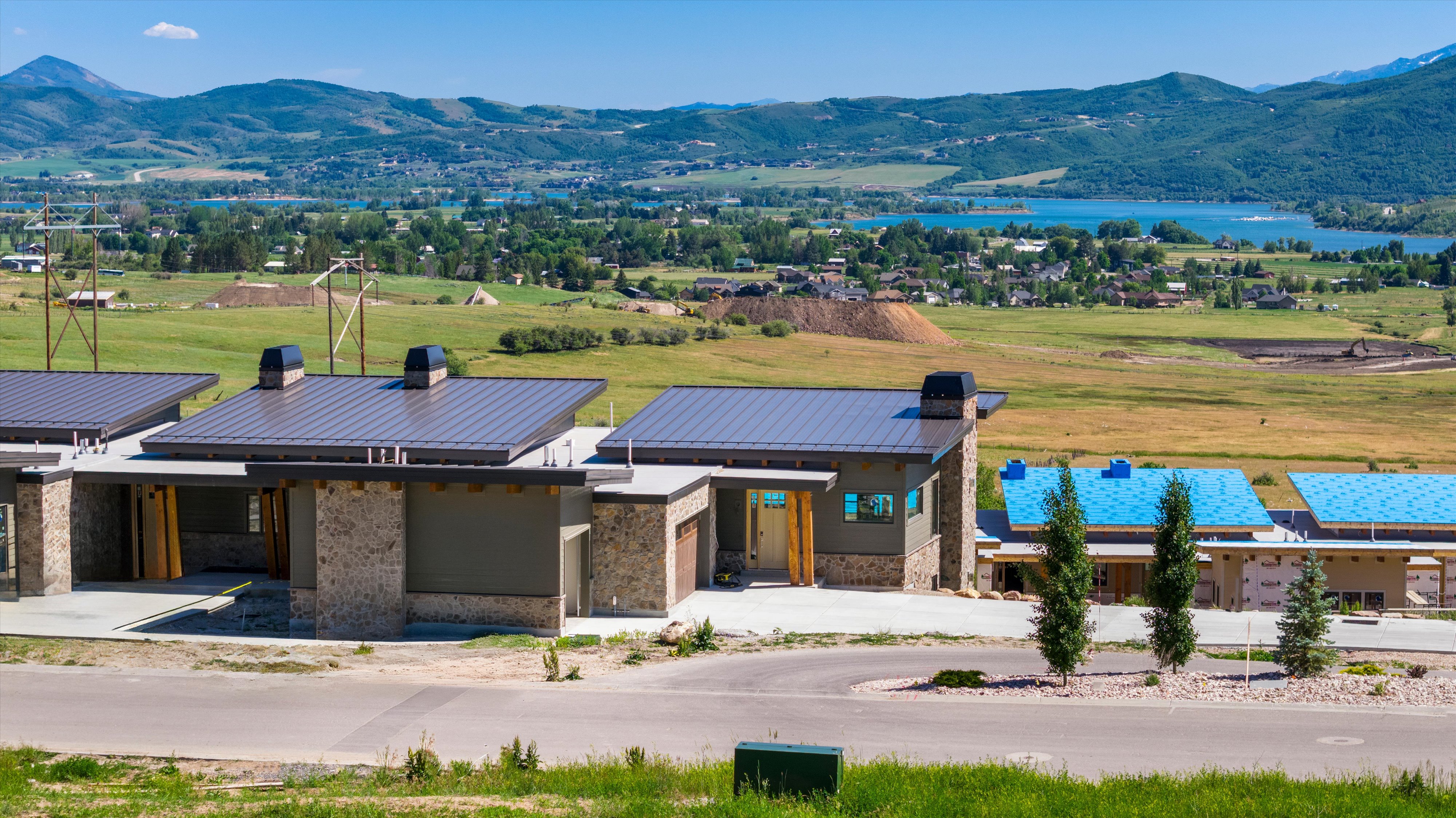Modern architectural design featuring a flat metal roof, stone facade, and a prominent wood-finished front entry