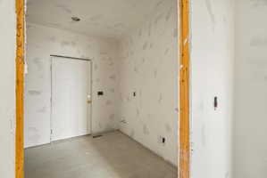 Interior space featuring gray tile flooring, a white paneled door with brass hardware, and recessed lighting
