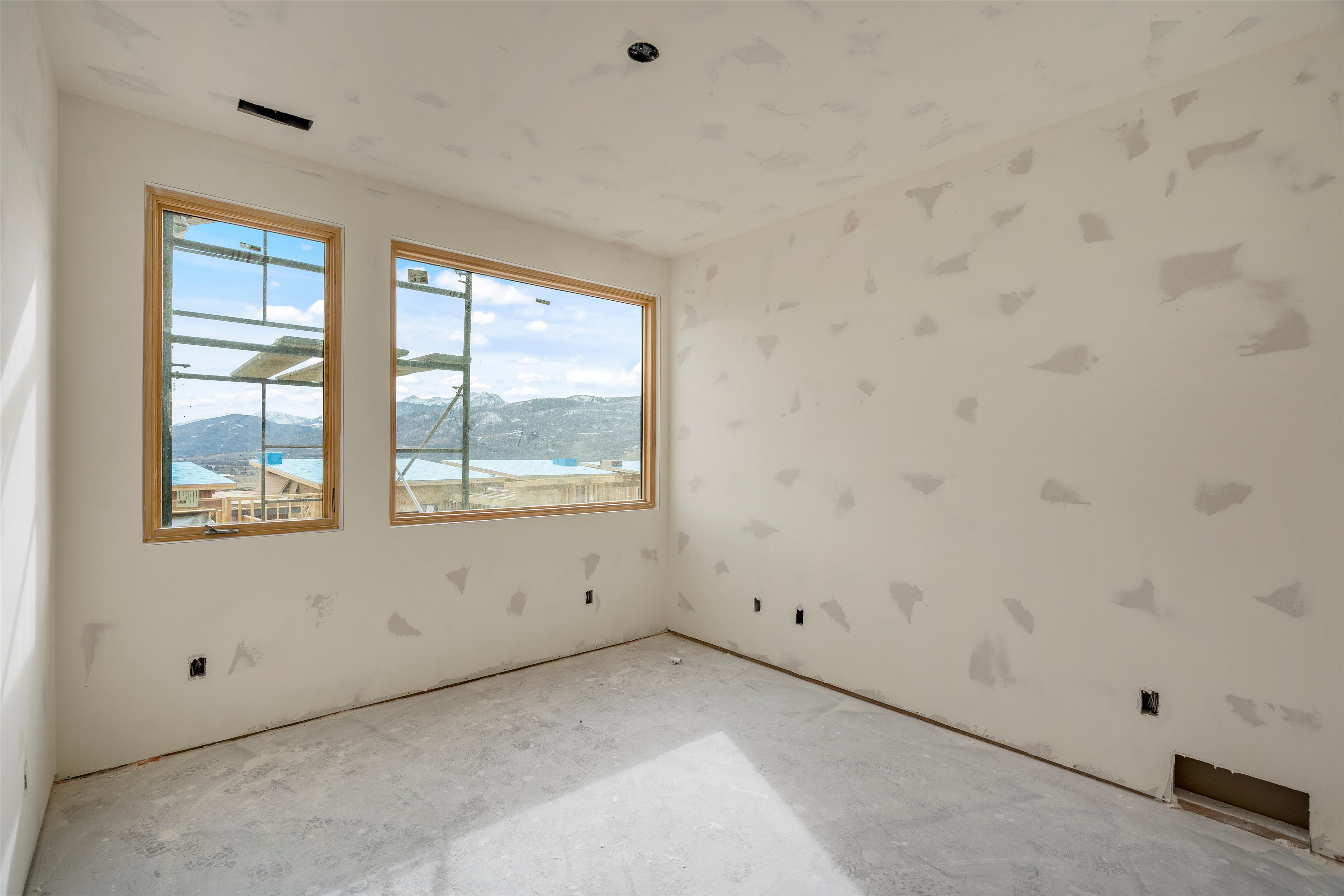 Room with two large windows showcasing distant mountains and a body of water