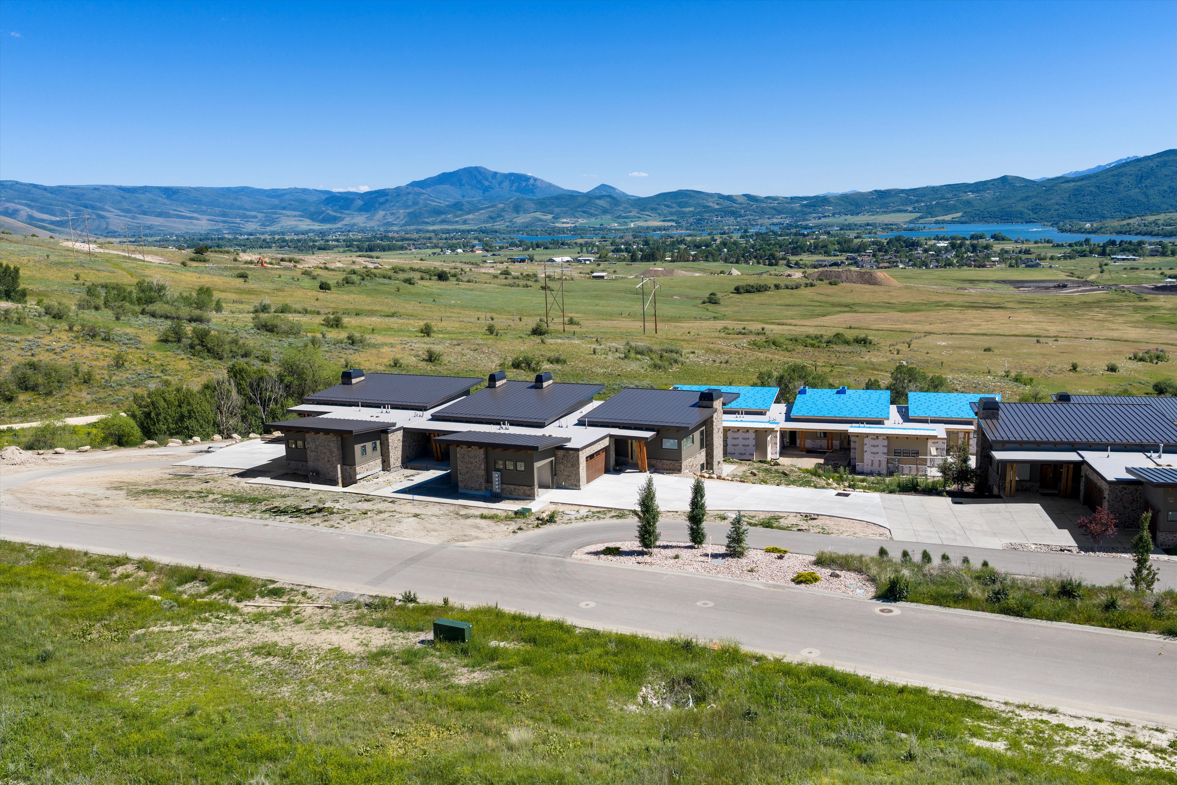 Modern residential development featuring stone and wood-paneled exteriors, dark metal roofs, and attached garages