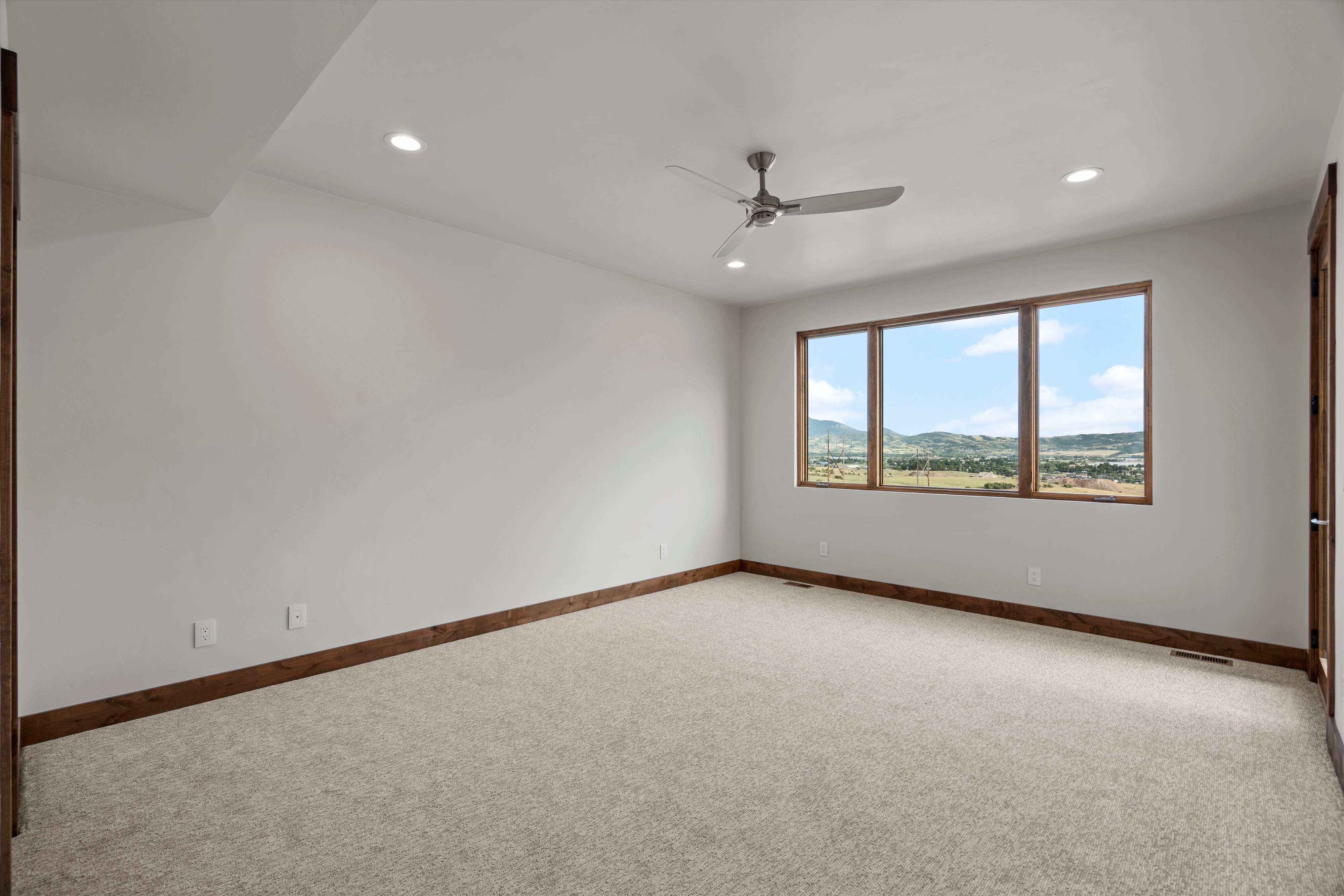 Spacious room featuring light-toned carpeting, recessed lighting, and a contemporary ceiling fan