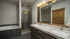 Full bathroom with double vanity, a shower stall, a bath, a textured ceiling, and recessed lighting