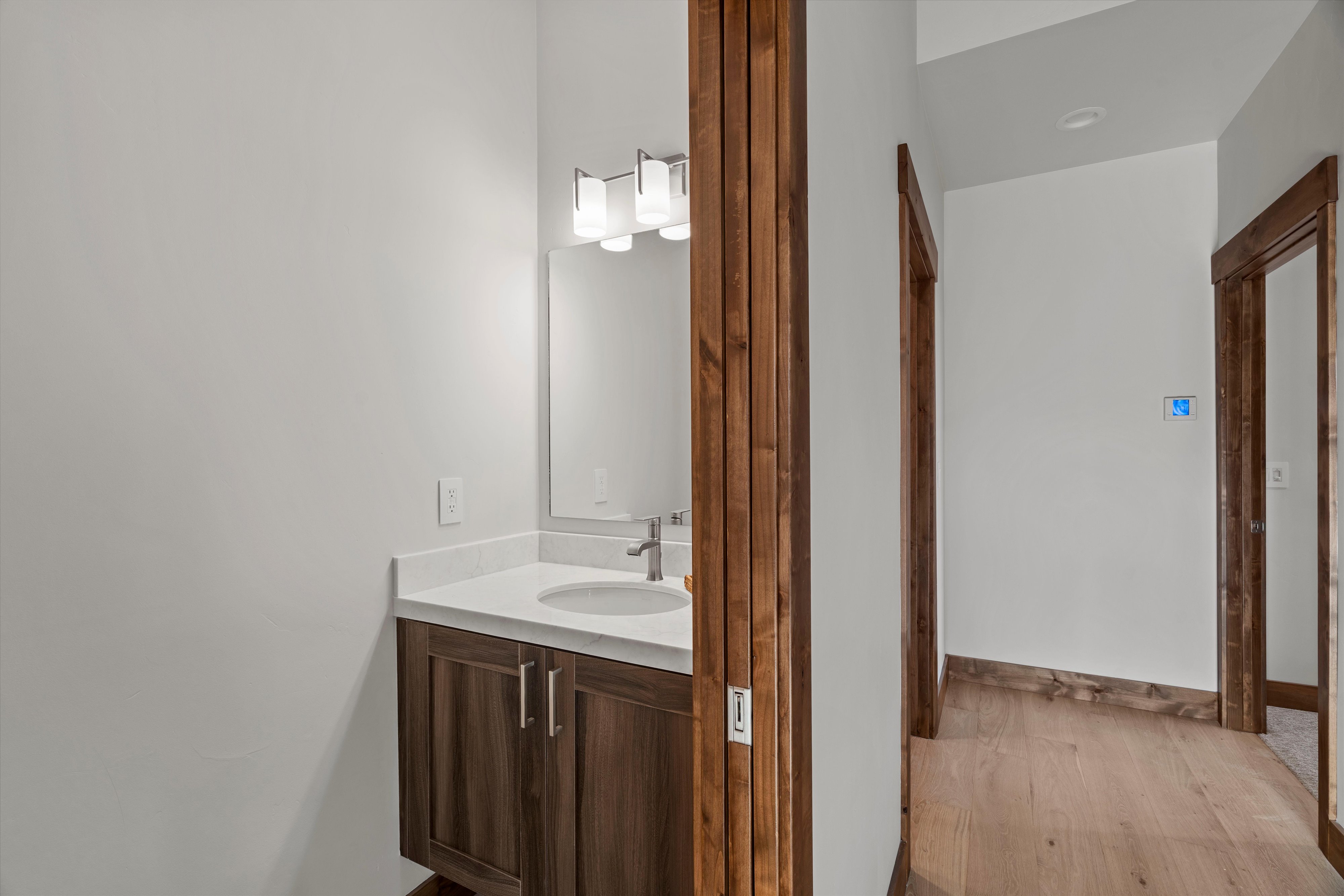 Bathroom vanity featuring a wood-finish cabinet, white countertop, and brushed nickel faucet