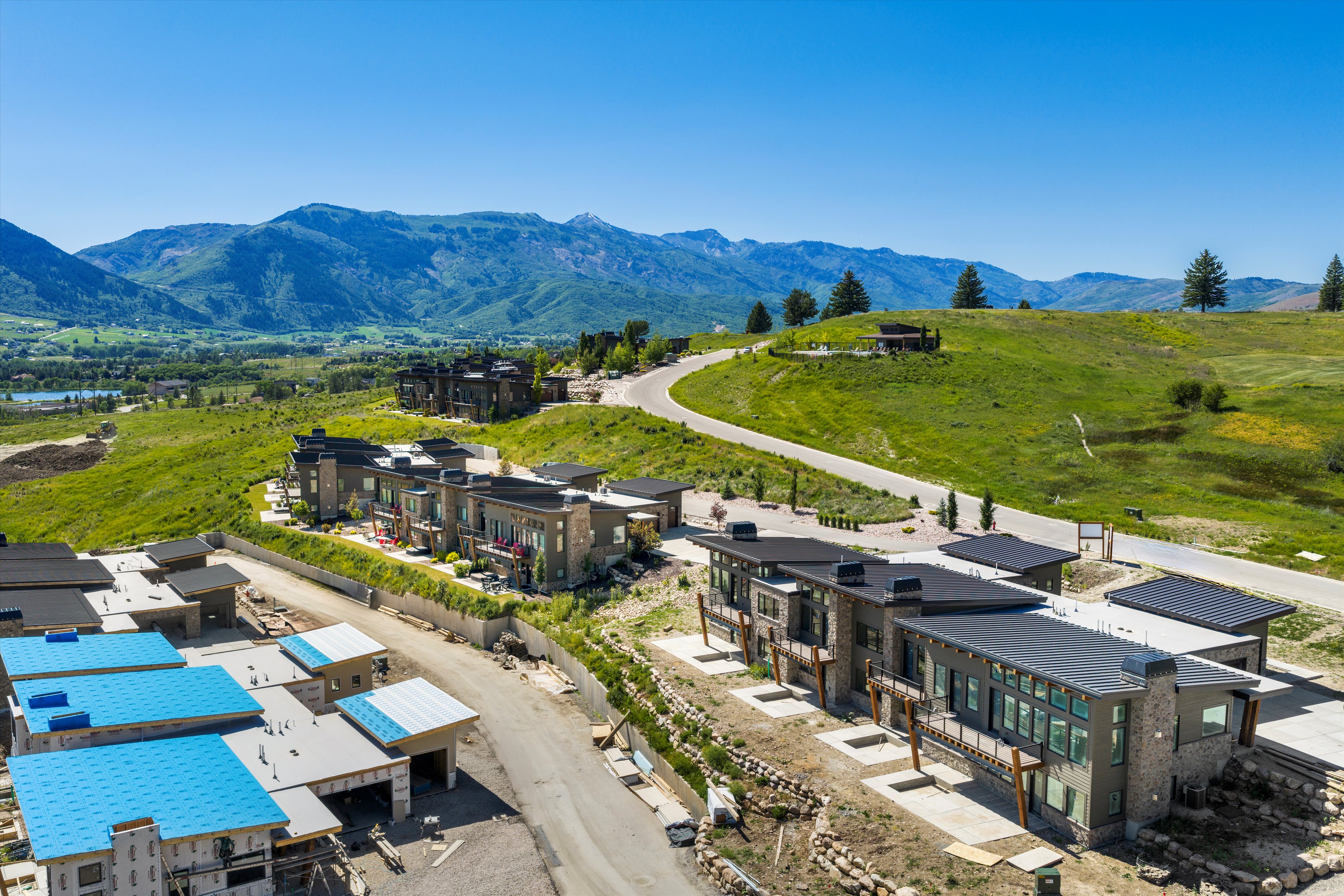 Contemporary residences featuring expansive windows, stone accents, and dark-pitched roofs