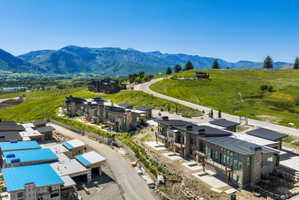 Contemporary residences featuring expansive windows, stone accents, and dark-pitched roofs