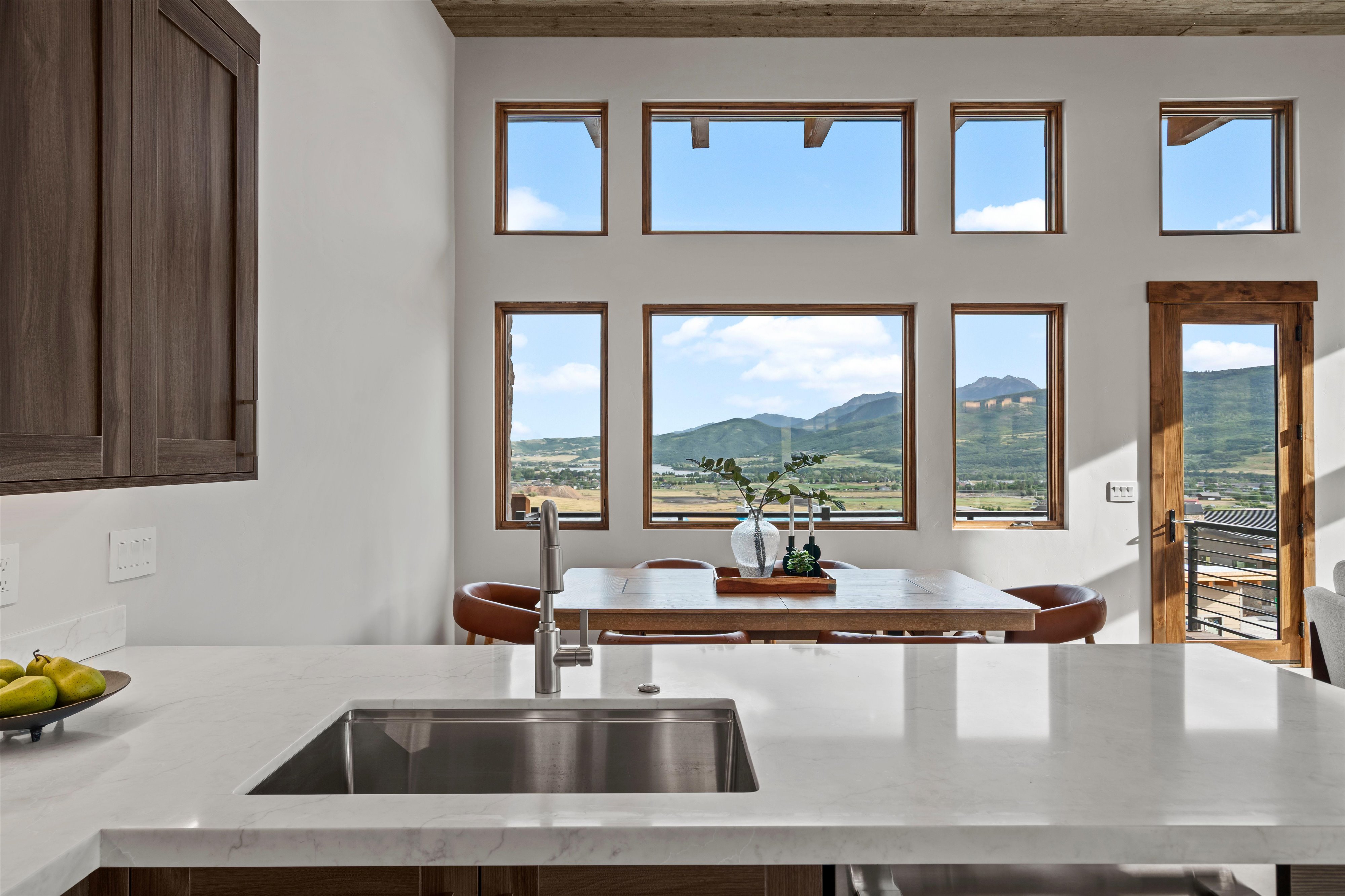 Kitchen island featuring a stainless steel sink and light-toned countertop, with dark wood-finish cabinetry