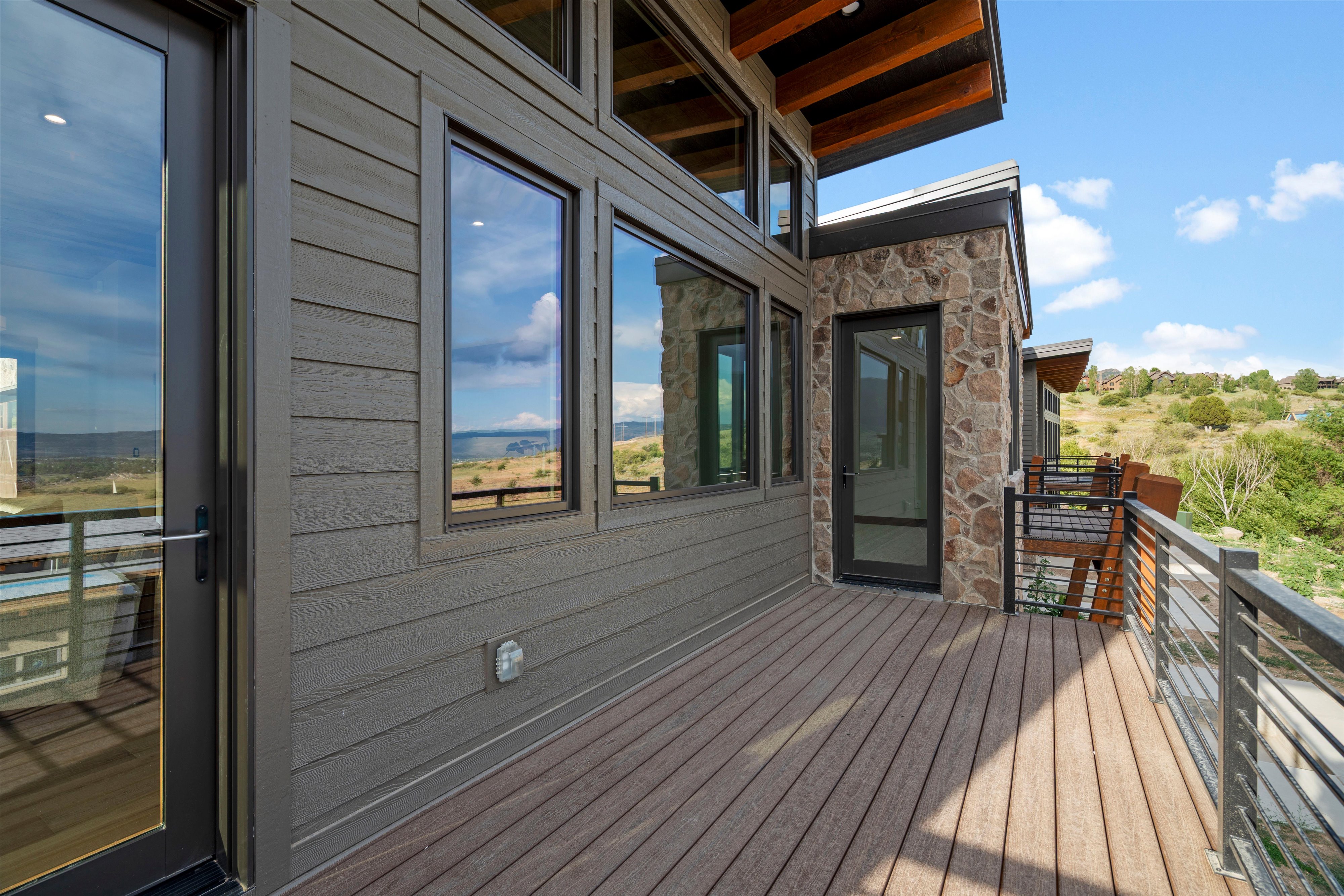 Exterior deck featuring wood-finish decking, horizontal siding, and stone accents