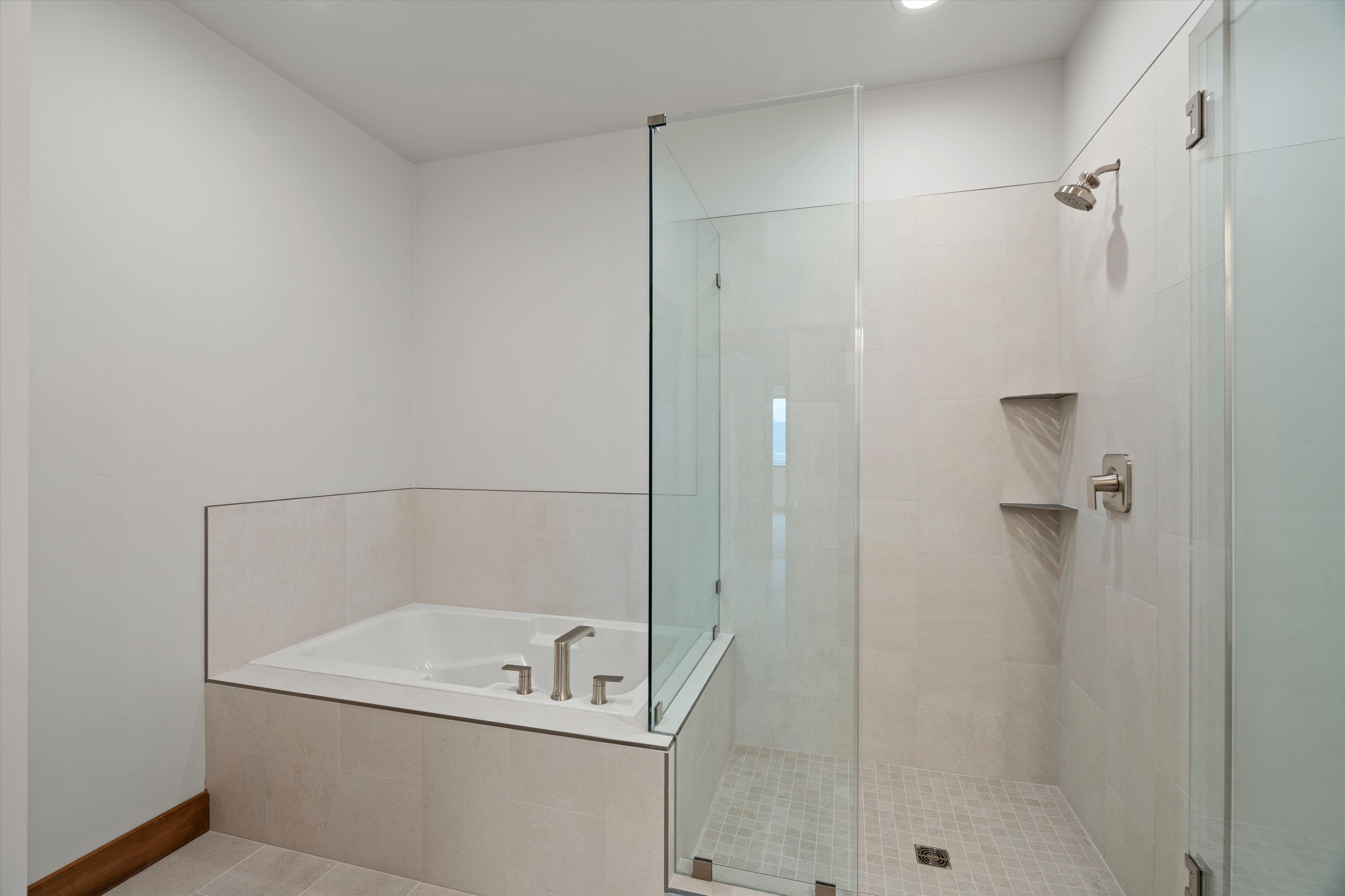 Contemporary bathroom featuring a glass-enclosed shower, built-in bathtub, brushed nickel fixtures, two recessed shower shelves, and tiled flooring