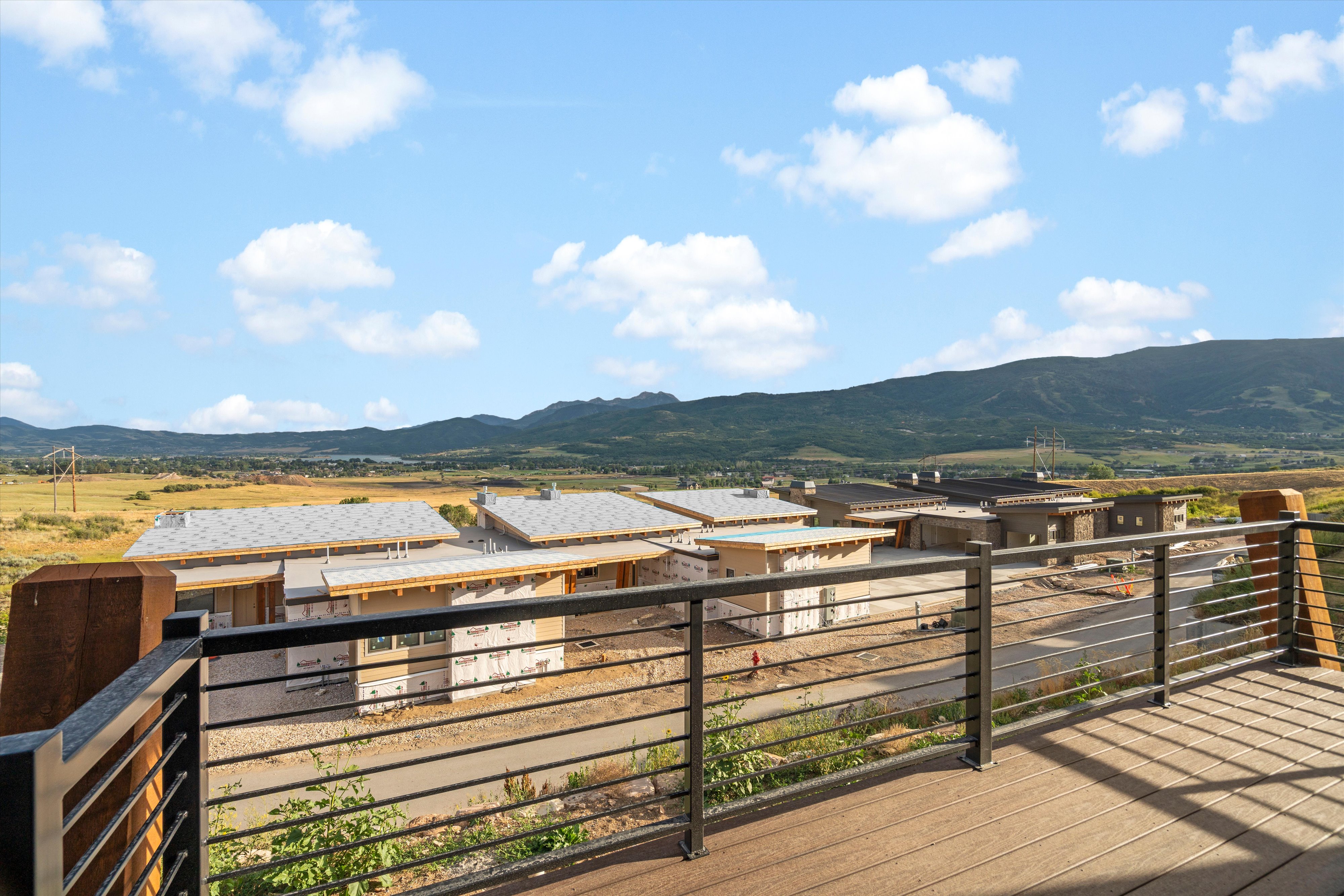Outdoor decking with a metal horizontal bar railing system, featuring a mountain range backdrop and distant properties