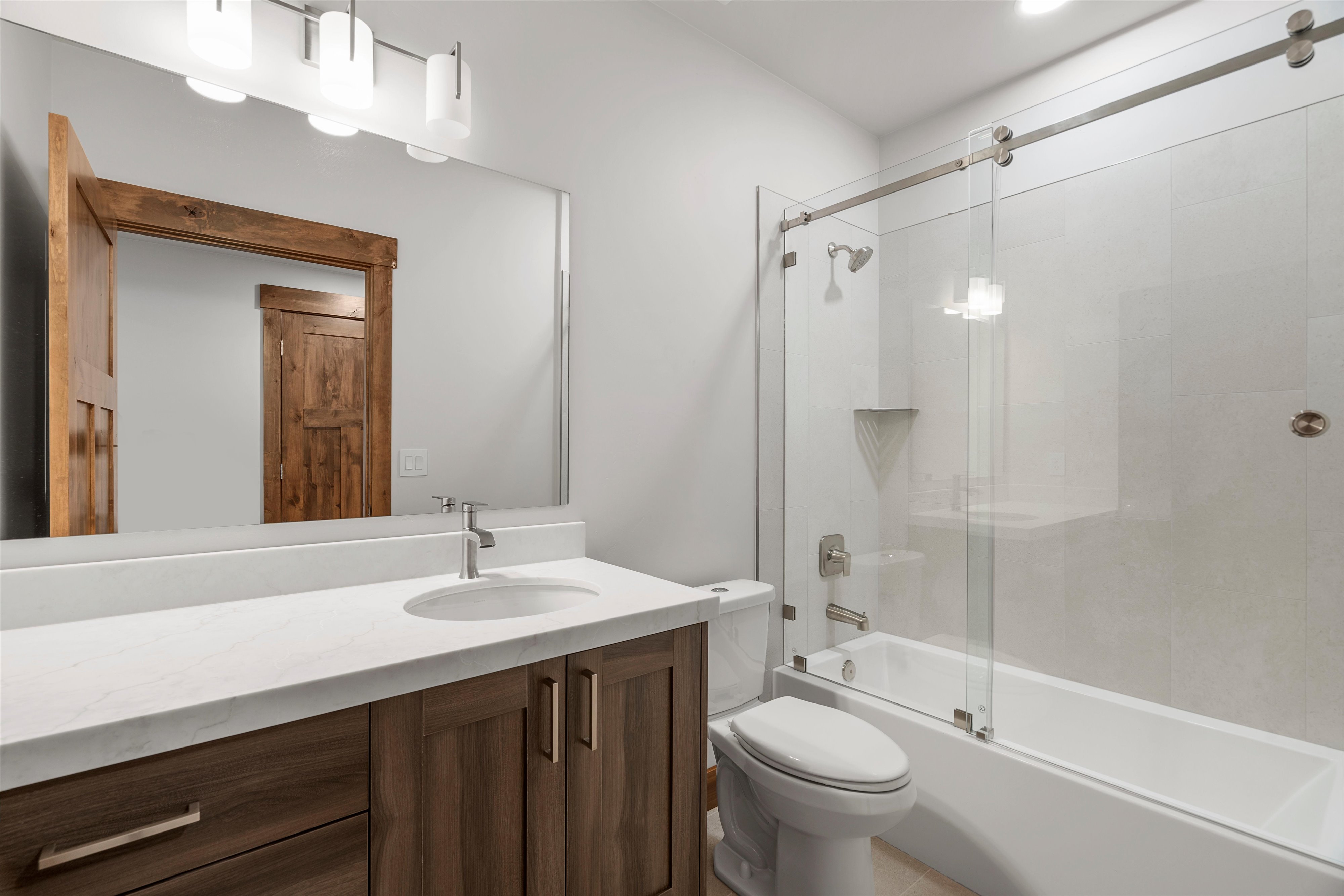 Bathroom featuring a wood-finish vanity with a light-colored countertop and undermount sink