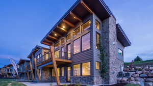 View of property exterior with stone siding, a balcony, and a patio