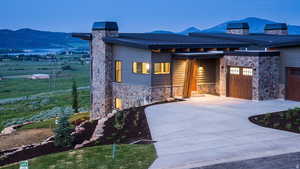 View of front of property featuring a chimney, stone siding, concrete driveway, a mountain view, and an attached garage