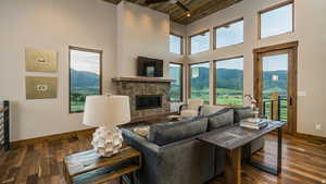 Living room with dark wood-style flooring, a fireplace, a high ceiling, wood ceiling, and plenty of natural light