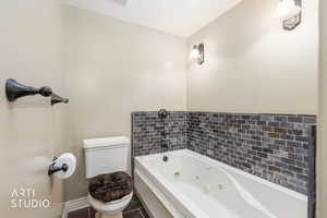 Full bathroom featuring a tub with jets and toilet