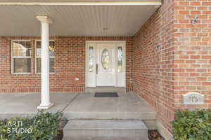 Property entrance with covered porch and brick siding