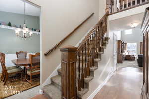 Staircase with a chandelier, a high ceiling, and wood finished floors