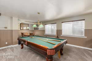 Game room with a wainscoted wall, billiards table, carpet, a textured ceiling, and wood walls