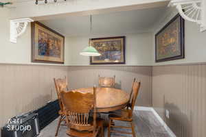 Carpeted dining room with a wainscoted wall