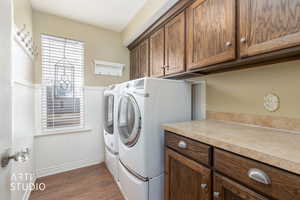 Washroom featuring dark wood-style floors, cabinet space, wainscoting, and independent washer and dryer