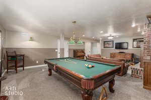 Rec room featuring wainscoting, carpet, billiards table, a textured ceiling, and wooden walls
