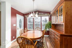 Dining space with a chandelier, light wood-style floors, and lofted ceiling