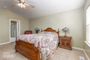 Bedroom featuring lofted ceiling, a ceiling fan, light colored carpet, and ensuite bath