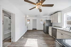Kitchen featuring white cabinets, stainless steel appliances, light wood finished floors, and a ceiling fan