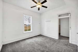 Carpeted spare room with a ceiling fan and baseboards