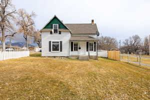 View of front of house with a porch, a chimney, roof with shingles, and a gate