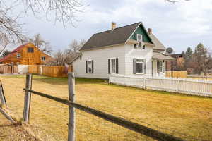 View of side of property featuring a chimney, a fenced backyard, and roof with shingles