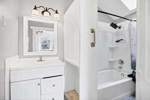 Full bath featuring vanity, shower / bath combo with shower curtain, and a skylight