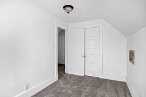 Additional living space featuring dark colored carpet and lofted ceiling