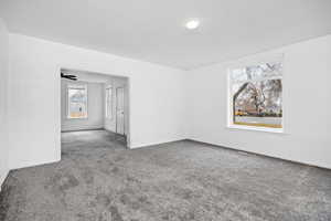 Carpeted empty room with baseboards and a ceiling fan