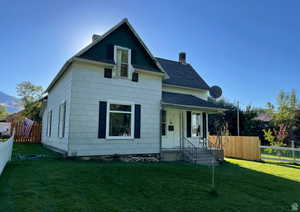 View of front facade with a chimney, roof with shingles, and covered porch