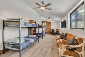 Bedroom with vaulted ceiling, light colored carpet, a textured ceiling, and a ceiling fan