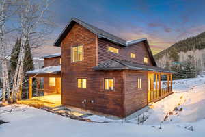 View of snow covered exterior with a metal roof and a patio