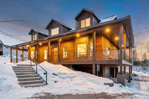 Chalet / cabin with a porch, faux log siding, and a metal roof